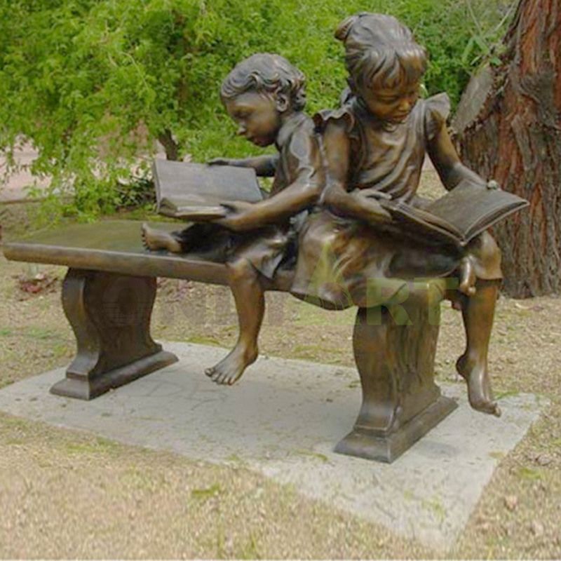 A sculpture of two children reading together on an apartment bench