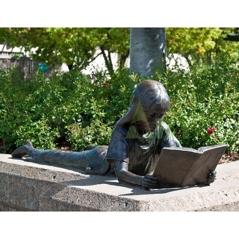 The girl leans on the stone and looks at the book in her hand with relish