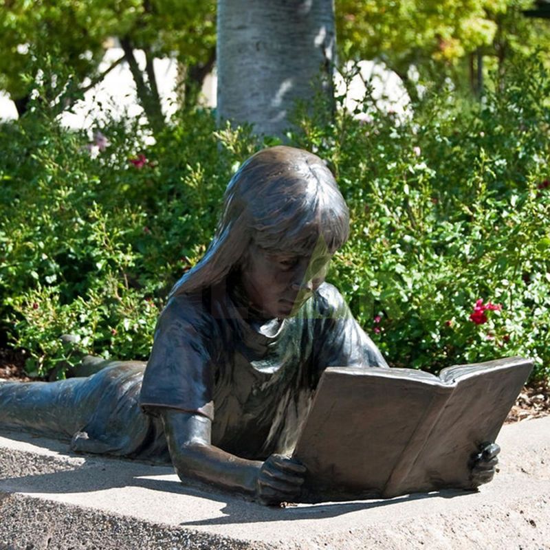 The girl leans on the stone and looks at the book in her hand with relish