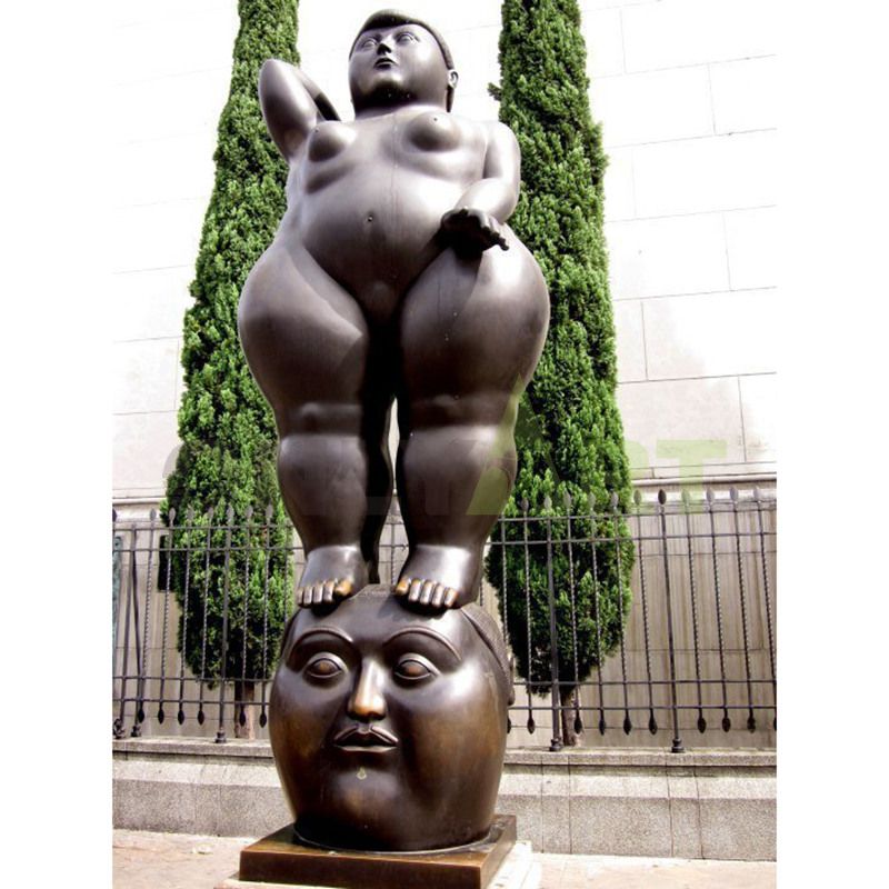 The standing portly woman is walking on the head sculpture