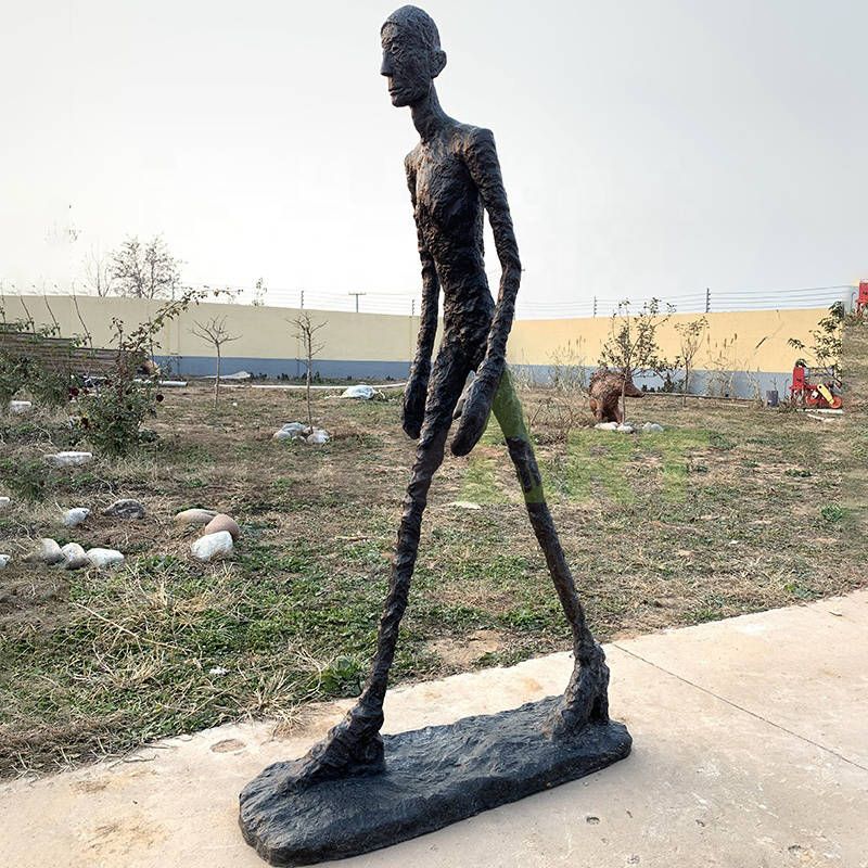 A black bronze statue of a man strides forward