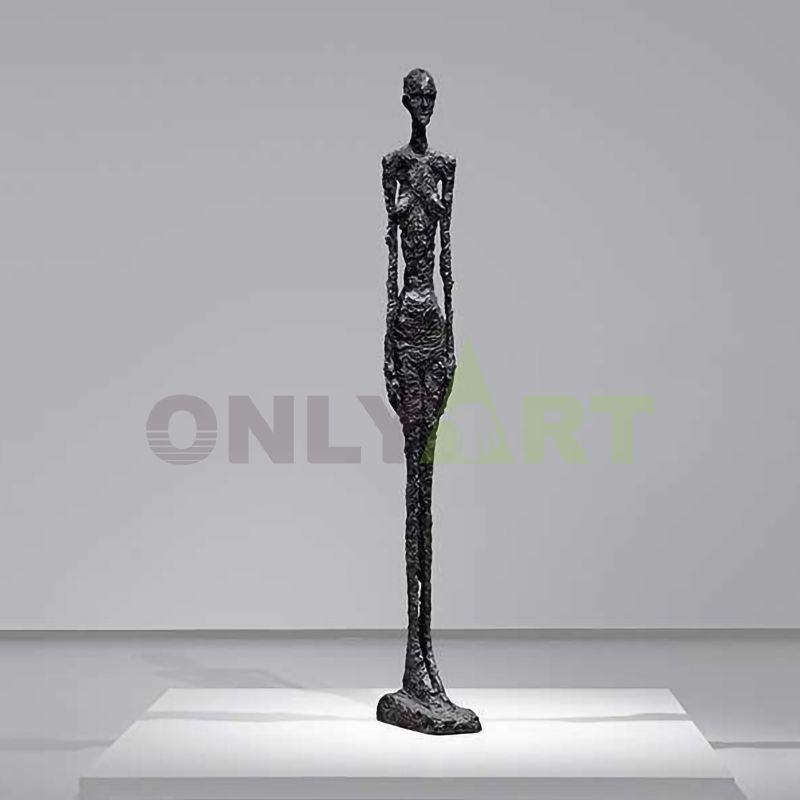 A black bronze statue of a man strides forward