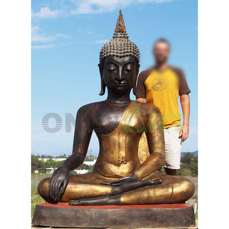 The head of a Buddha is silhouetted against the sky