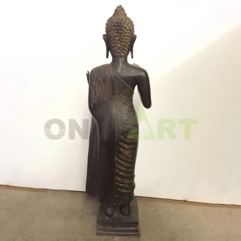 A bronze statue of a standing Buddha