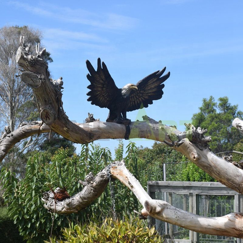 A bronze eagle with wings spread on a branch