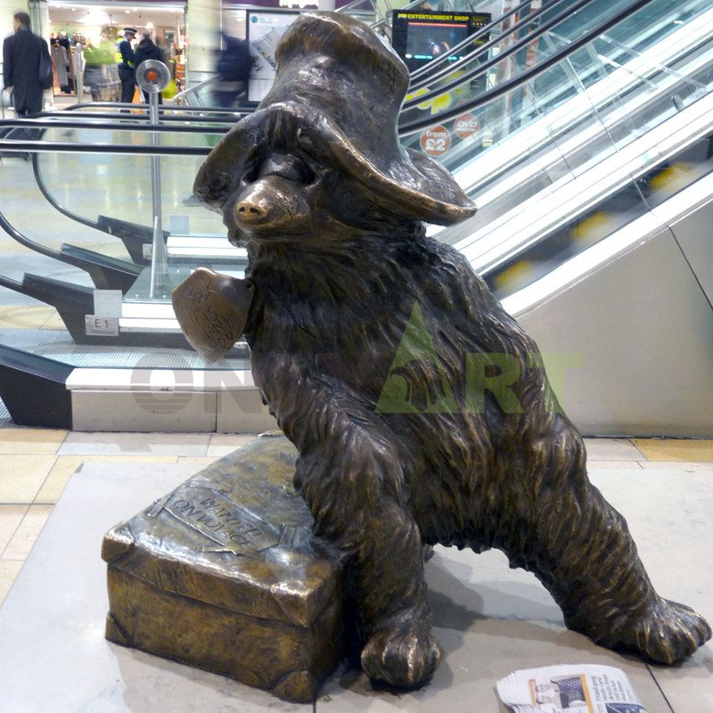A bronze sculpture of a brown bear carrying a suitcase for a trip is for sale