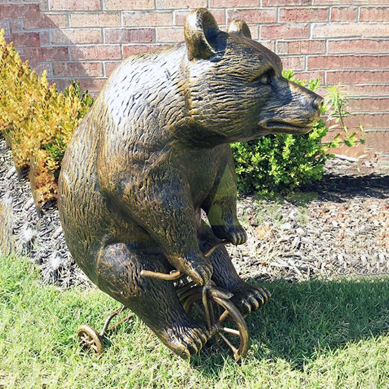 A bronze sculpture of a brown bear riding a bicycle is on sale