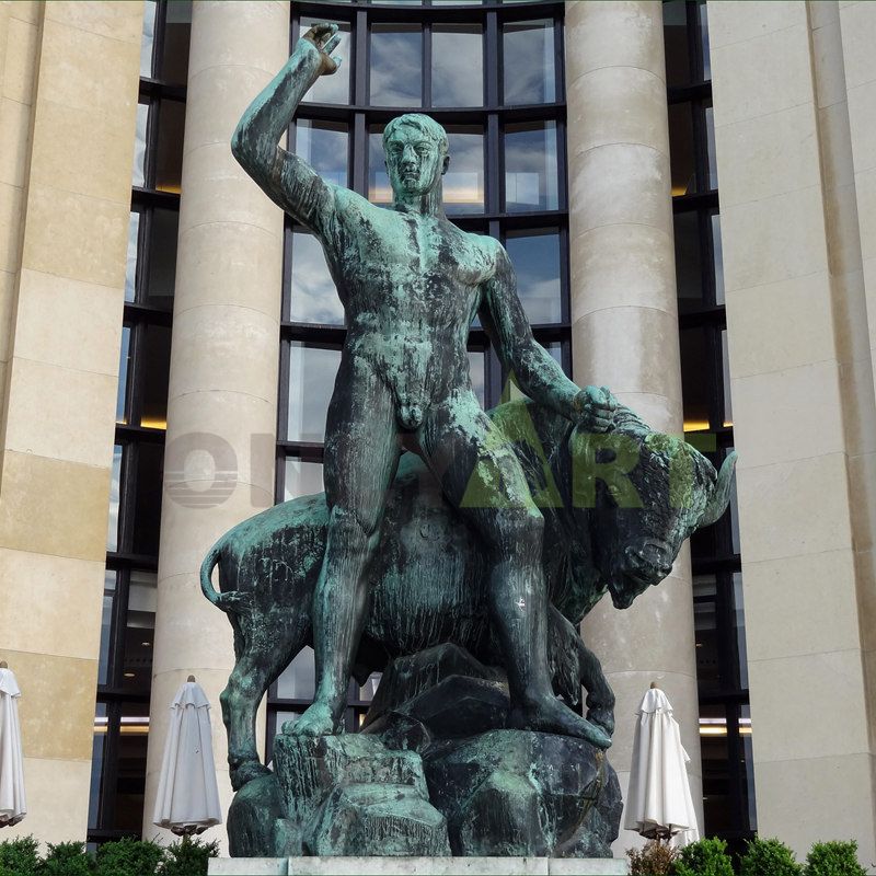 A life-size antique bronze statue of an outdoor bull and a standing naked man