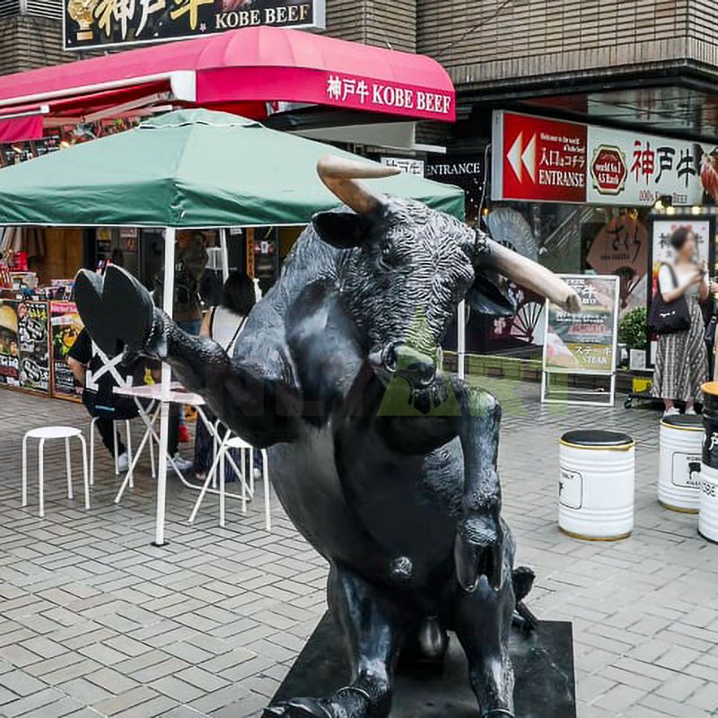 A life-size antique bronze statue of an outdoor bull and a standing naked man