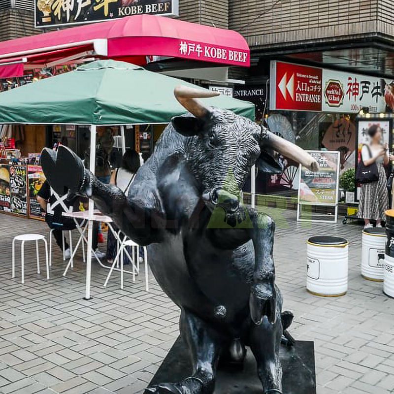 A bronze statue of a cow resting on its rear view