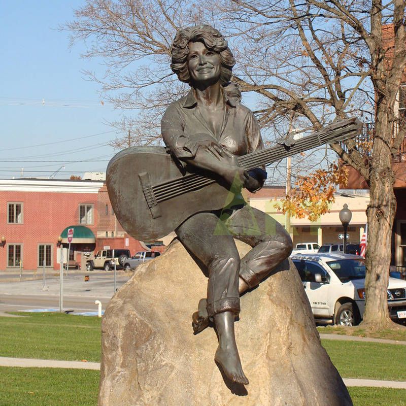 A woman musician dressed simply and seated on a stone