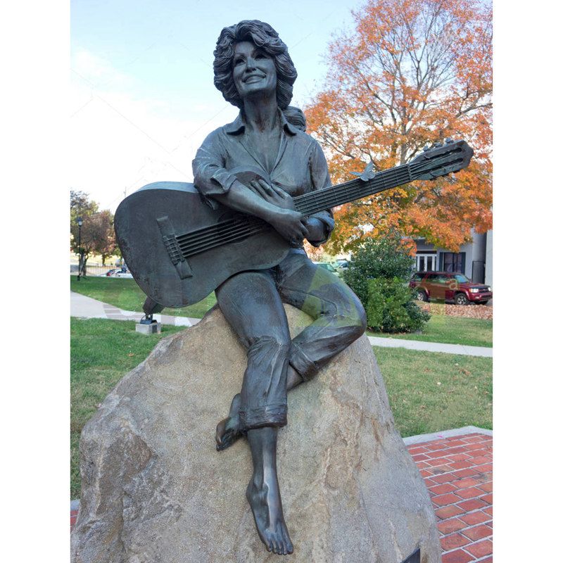 A woman musician dressed simply and seated on a stone