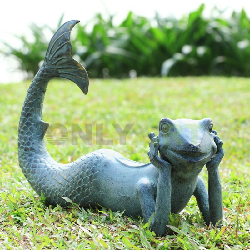 A sculpture of a frog sitting on a wicker chair holding a book